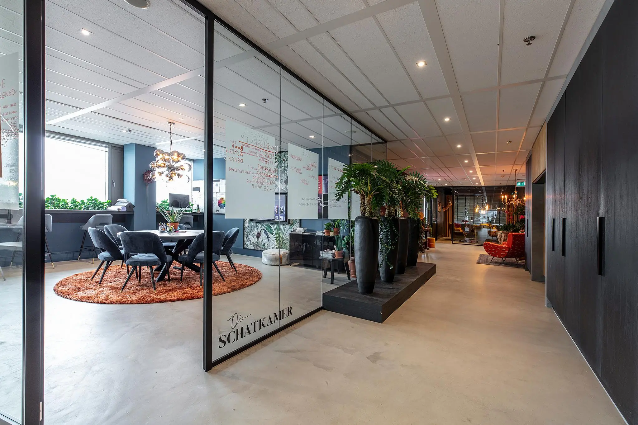 Moderne kantoorruimte aan de Vliegend Hertlaan met glazen vergaderruimte genaamd "De Schatkamer", stijlvolle meubels en veel groen.